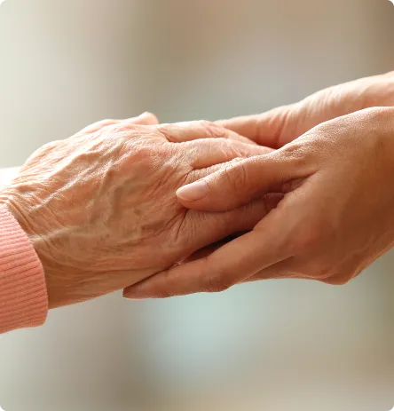 Close up image of an older woman and younger woman holding hands