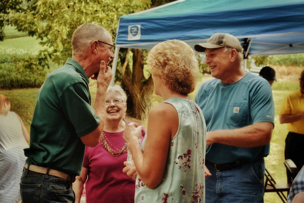 A group of seniors talks at an outdoor event.