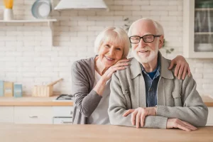 An elderly couple smiling in a bright kitchen space.